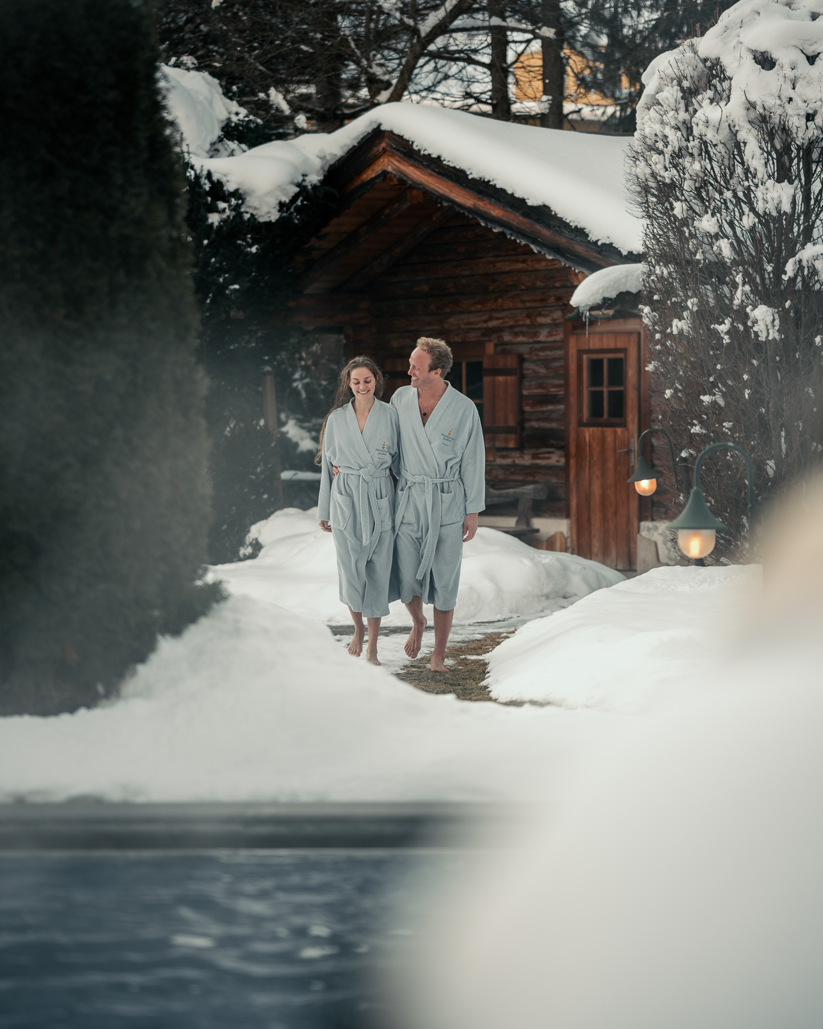 Ein Paar wandert im Bademantel durch den Schnee.